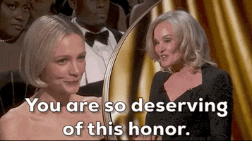 Oscars 2024 GIF. Split screen of Jessica Lange speaking sincerely to Cary Mulligan, who smiles bashfully. Lange says, "You are so deserving of this honor."