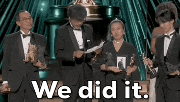 Oscars 2024 gif. The Godzilla Minus One team wins Visual Effects. Takashi Yamazaki reads from a sheet of paper, "We did it" while looking up towards the crowd.  