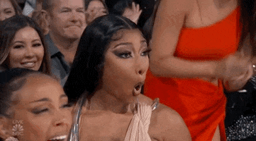 Celebrity gif. Megan Thee Stallion at the Billboard Music Awards 2022 looking honestly shocked while those around her gas her up and clap. 