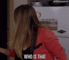 TV gif. Hilary Duff as Kelsey on Younger turns back around after looking over her shoulder. She has a confused, slightly irritated look on her face, as she says, “Who is that?”