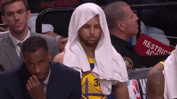 Sports gif. Steph Curry wears a towel over his head as he gazes blankly as if zoned out. 