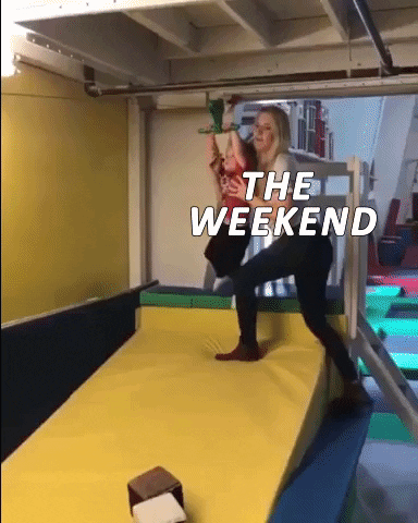 Video gif. A mother with the text, "The Weekend," overlaid on her body pushes her son down a small zipline. He zips down happily before hitting a wall at the bottom that says, "Monday," and falls to the cushion below. 