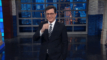 TV gif. Stephen Colbert as host of The Late Show steps toward us as he does the sign of the cross and then a chef's kiss before looking upward.