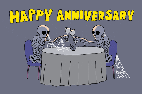 Pohyblivá animace se dvěma kostrami sedícími u stolu a připíjejícími si vínem s nápisem "Happy anniversary". 