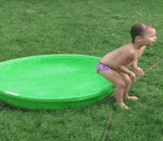 Video gif. In a clip from AFV, a child in a bathing suit prepares to drop into a seated position onto the side of a full plastic kiddie pool, ostensibly tipping it over...but instead they just land on the ground. The child looks at us with surprise.