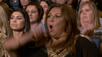 Reality TV gif. Abby Lee Miller from Dance Moms cheers "Woohoo" and claps proudly in the audience.