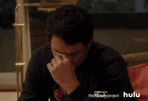 TV gif. Chris Messina as Danny Castellano on The Mindy Project sits on the edge of a couch, leaning forward and pinching the bridge of his nose in frustration. 