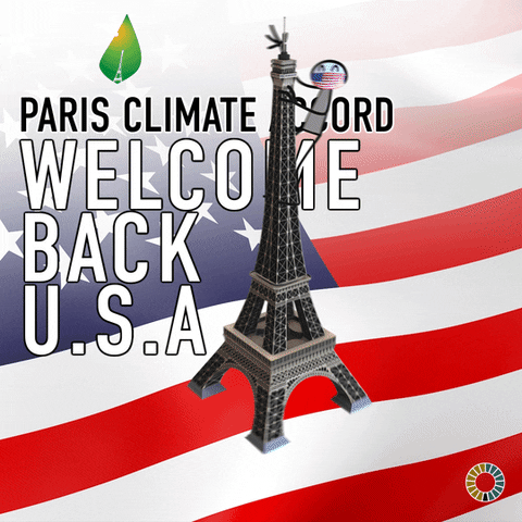 Digital art gif. Stick figure with American flag mask hangs onto the side of the Eiffel Tower, which spins around, floating above a flowing American flag background. Text, "Paris Climate Accord, Welcome Back U.S.A."
