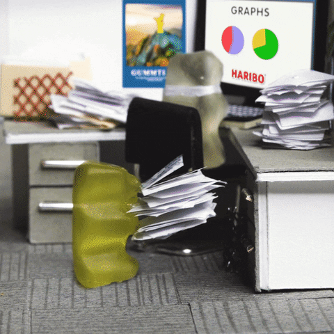 Ad gif. Yellow Haribo gummy bear heaves a pile of papers onto the cluttered desk of a clear gummy bear, who faces a computer screen displaying pie charts, then turns around toward us, when a speech bubble appears that says, "Mondays."