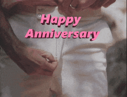 Video gif. Close-up of a man unzipping his pants, reaching in, and pulling out a pink flower. Text, "Happy anniversary."