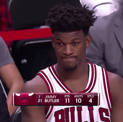 Celebrity gif. NBA Player Jimmy Butler on the Chicago Bulls sits on the sidelines looking out at the court. He’s concentrated on the game until something shocks him, and he blinks in confusion. He looks away with squinted eyes and pursed out limps, still super confused about what he just witnessed.