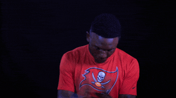 Sports gif. Tampa Buccaneers football player Chris Godwin claps as if satisfied.