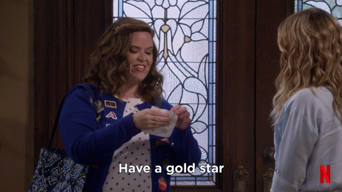 Gif of a woman putting a sticker onto another woman's shirt saying: Have a gold star!