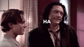 Movie gif. Tommy Wiseau as Johnny in The Room. He walks out of a room and sarcastically says, "Ha ha ha."