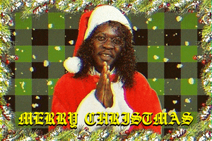 Video gif. Black man dressed as Santa with round glasses looks at us nodding with a smug frown and rubs his hands together as he says, “Merry Christmas.” Snow falls behind him on a green plaid background.
