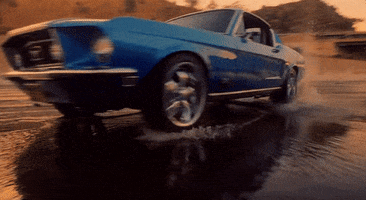 Music video gif. From the Rolling Stones video for "Ride Em All Down," a blue 1960s Ford Mustang makes a sharp U-turn on wet pavement, and its back wheel splashes water at us.