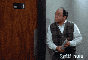 Seinfeld gif. Jason Alexander as George Costanza stands outside of the Men’s bathroom with a notepad and pencil. He looks at the time and rolls his eyes impatiently. 
