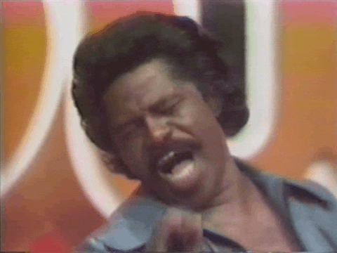 Celebrity gif. James Brown performing while seemingly intoxicated, twirling around and fumbling, swinging the mic stand.