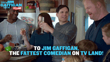 Ad gif. A group of people stand around Jim Gaffigan in a kitchen, three children next to him and three adults smiling at him holding champagne glasses. Michael Ian Black as Daniel toasts Jim and says, "To Jim Gaffigan, the fattest comedian on TV Land!" 