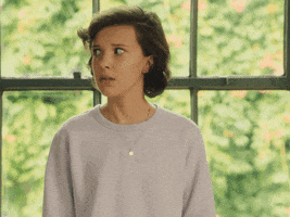 Celebrity gif. Confused Millie Bobby Brown turns toward us and holds her hands up in an uncomfortable shrug as if to say, “I have no idea.”