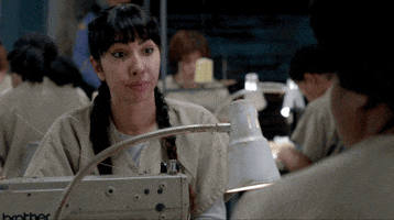 TV gif. Jackie Cruz as Marisol in Orange Is The New Black. She is wearing her prison uniform and sits in front of a sewing machine. She purses her lips and nods matter of factly, in agreement with her friend.