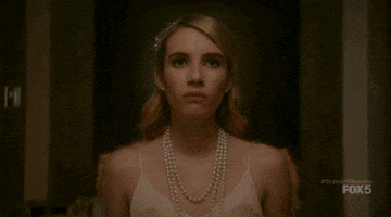 TV gif. Emma Roberts as Chanel Oberlin in Scream Queens stands up from the dining table defiantly, pointing her finger and spitting “how dare you.”