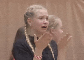 Video gif. A girl with braids and braces looks uncomfortable as she fans her face with her hands. 