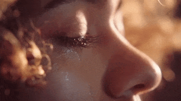 Music video gif. Close up of Starley’s eye in the Call on Me Ryan Riback Remix Music video. Tears soak her cheeks as she opens them slowly. Golden light hits her face.