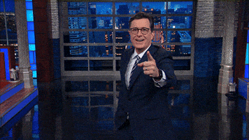 Late Show gif. Stephen Colbert points at us expectantly, looking excited and he juts his finger out even more as he says, "Ah ha!" as if he's caught us in the act.