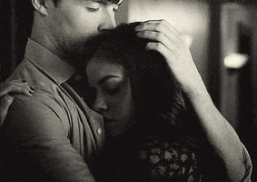 TV gif. Ian Harding as Ezra comforting Lucy Hale as Aria from Pretty Little Liars with an embrace, patting her hair.