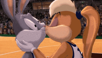 Cartoon gif. In Space Jam, Lola Bunny kisses Bugs Bunny and then turns to jog away on a basketball court, while Bugs' face bursts into a goofy smile with hearts in his eyes.
