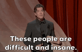 Oscars 2024 gif. With a deadpan expression, John Mulaney says, "These people are difficult and insane" while presenting at the Oscars.
