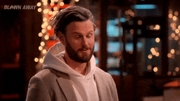 Reality TV gif. Bobby Berk on Blown Away raises an eyebrow and turns his head as if interested. 