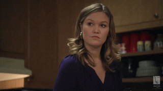 TV gif. Julia Stiles as Blue in Wigs, eyebrows raised, gestures with her hand presenting something unsaid.