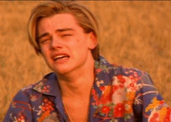 Movie gif. Leonardo DiCaprio as Romeo in Romeo + Juliet. He sits in a field during golden hour and is sobbing by himself. He chokes in air as he weeps and he is filled with anguish.