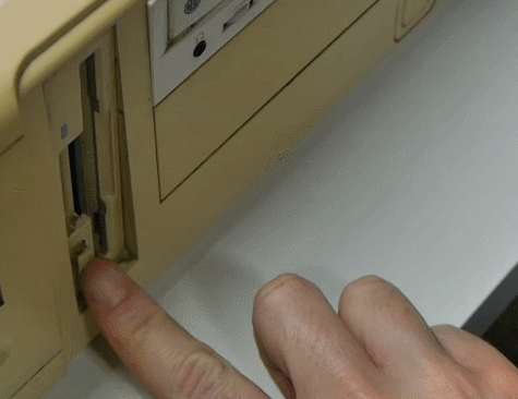 Old school floppy disk being ejected from old school computer