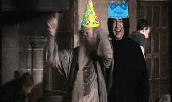 Digital art gif. Behind the scenes shot from Harry Potter with Richard Harris as Dumbledore dancing and Alan Rickman as Snape smiling at us, both of them wearing colorful clip-art party hats.