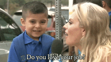 Video gif. Blonde woman holds a microphone up to a small boy. She says, "Do you love your job?" The boy responds with a questioning, "Yes?" The boy smile fades and he buries his face in his hands and walks away.