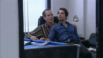 Arrested Development gif. A man sits in Gob Bluth's lap in the office. The two gently rock back and forth in the office chair. 