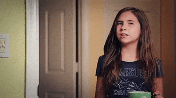 Video gif. Girl holding a mug turns toward us slowly with a questioning look and says, "I'm confused."