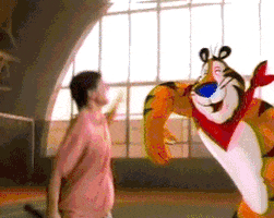 Ad gif. Tony the Tiger from Frosted Flakes jumps up in unison with a guy who carries a racket and they celebrate with a big air high five.