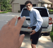 Video gif. Two young men in glasses and suspenders run towards a 4x4 car and write = 16 next to it. They both scurry away and film themselves giggling while running.