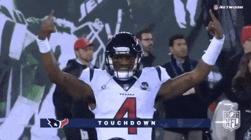 Sports gif. Houston Texans quarterback Deshaun Watson raises his arms and grins confidently to celebrate a Texans touchdown.