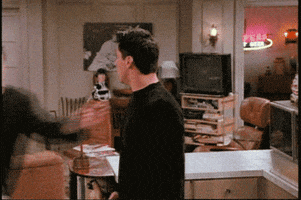 Friends gif. Matthew Perry as Chandler and Matt Leblanc as Joey stand shocked as Chandler runs and jumps in fear into Joey's arms. 