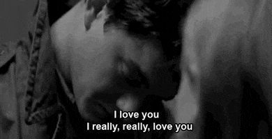 Video gif. Black and white video of a woman as she leans into a sad man saying, “I love you, I really, really love you.”