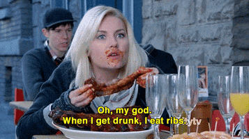 TV gif. Elisha Cuthbert as Alex on Happy Endings sits outside at a restaurant with at least six empty wine glasses on the table. She leans over the table, holding a rib in her hand with a whole plate of ribs in front of her. She has a wide-eyed look on her face with barbeque sauce smothered over her mouth. She says, “Oh, my god. When I get drunk, I eat ribs.”