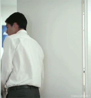 Celebrity gif. Football player Luis Suarez wears a suit and tie. He has his back turned in a doorway,and suddenly he jolts around like he was scared by someone. He then tried to casually lean on the doorframe. 