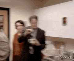 The Office gif. Rainn Wilson as Dwight slyly dips a teabag in and out of a mug of hot water as Leslie David Baker as Stanley and Phyllis Smith as Phyllis look on, giggling.