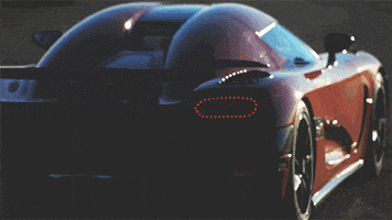 Video gif. A red Koenigsegg Agera drives away from us on a long country road.