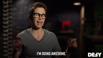 Reality TV gif. A Forged in Fire contestant wearing a gray t-shirt and glasses smiles as she tells us: Text, "I'm doing awesome."